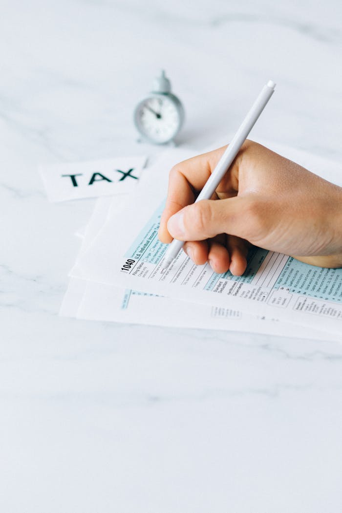 services-06 Hand completing tax forms with a pen, symbolizing financial deadline and time urgency.